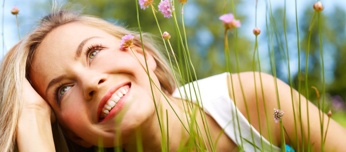 Attractive girl dreaming in a grass with flowers
